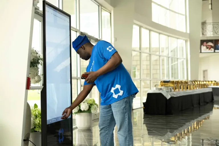 BlueBox team member setting up a floor-standing digital display at a venue entrance