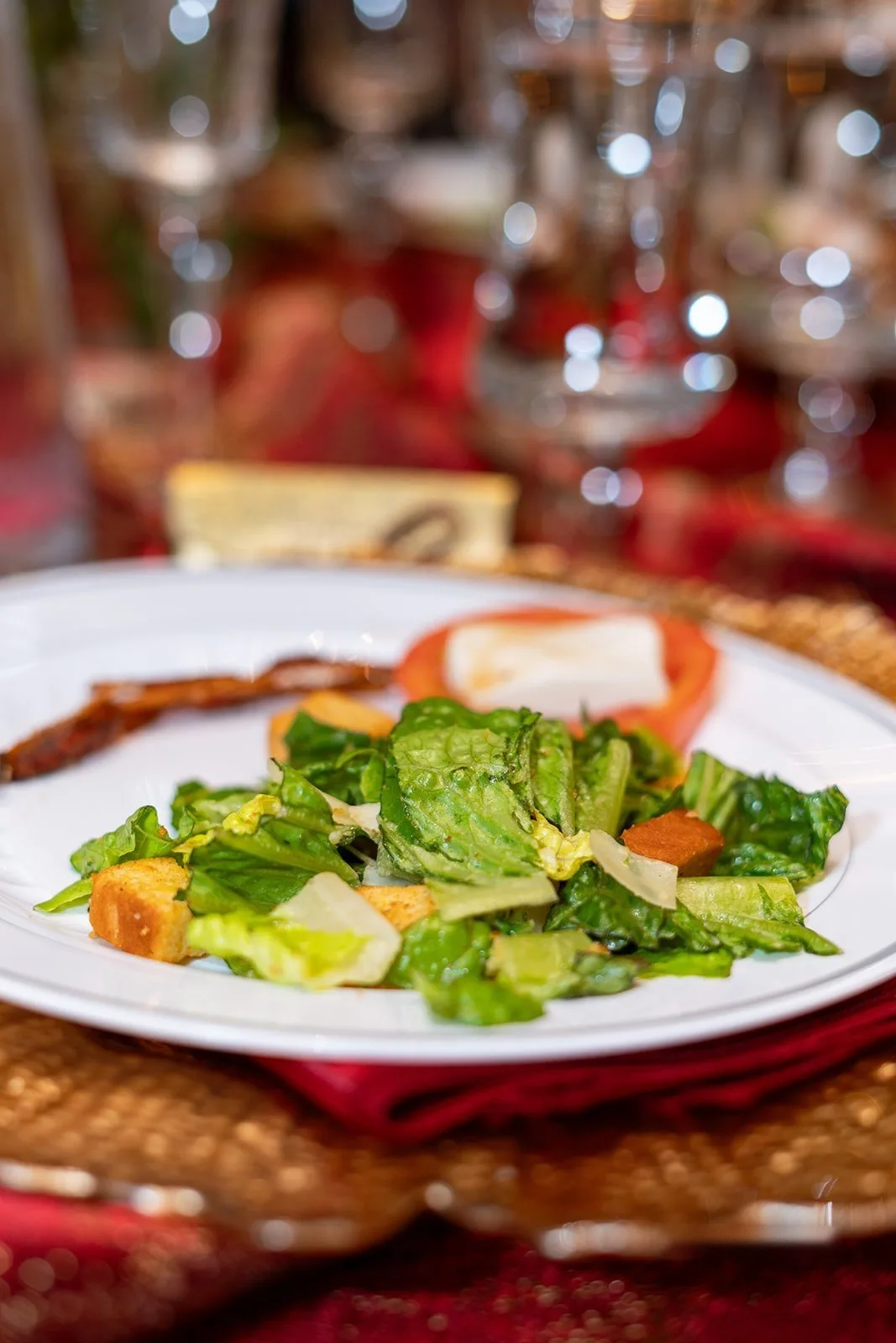 Plated Caesar salad on a gold charger at a reception table