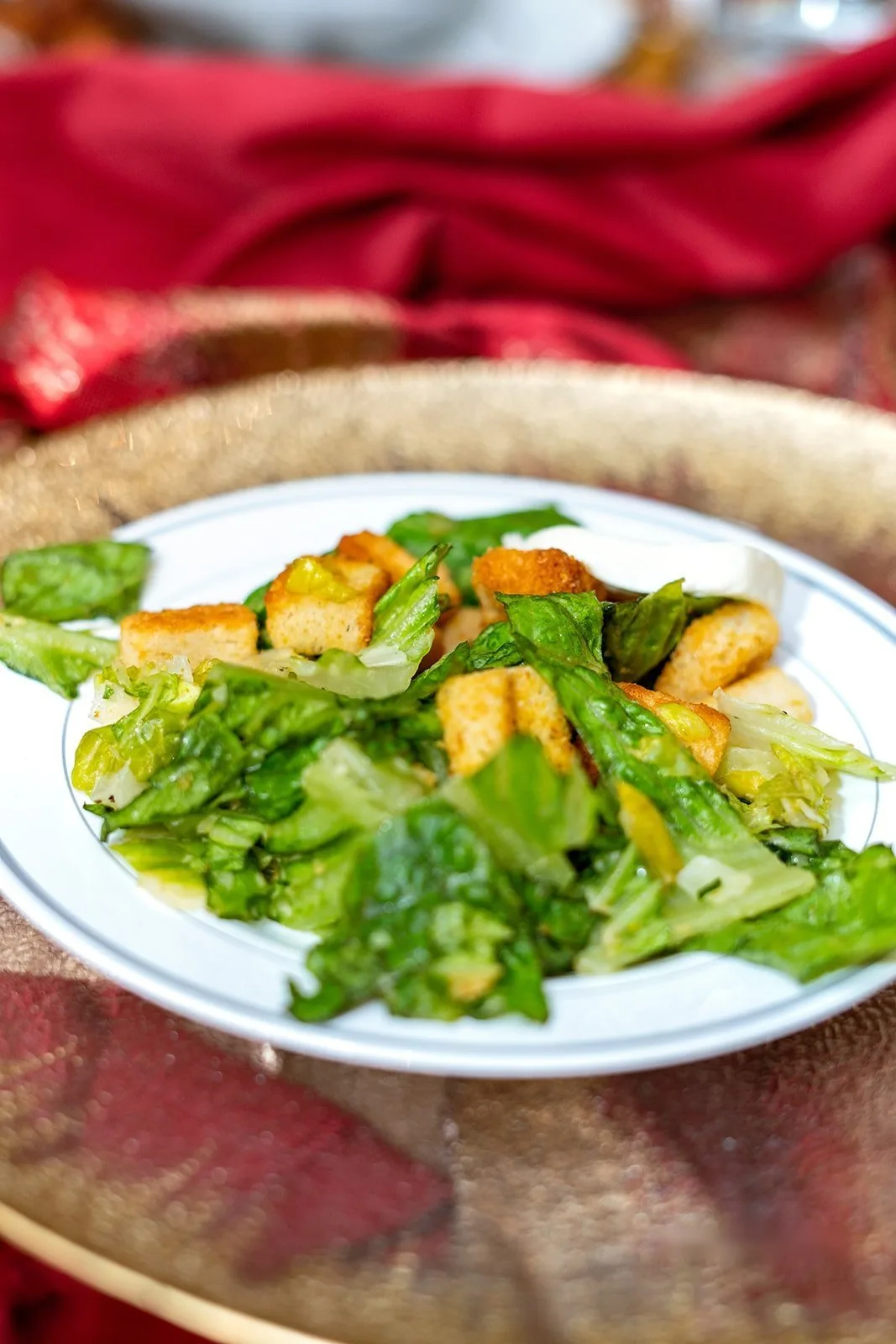 Garden Caesar salad with croutons on a white plate over a red table runner