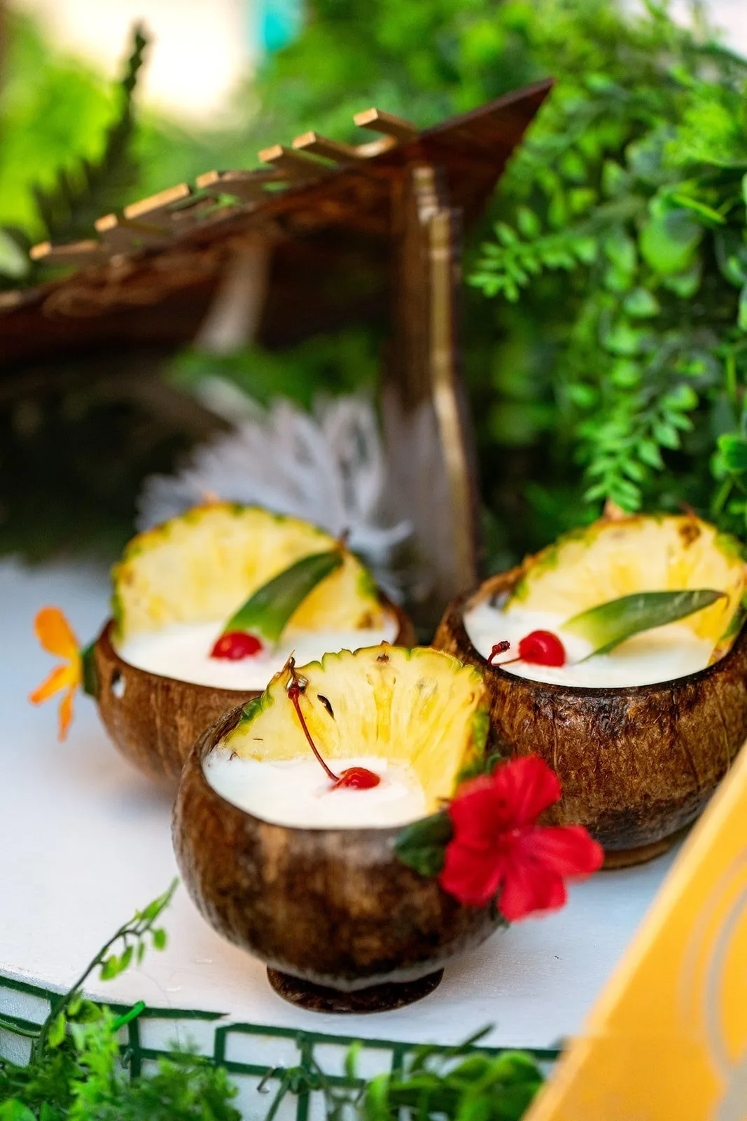 Piña colada served in coconut shells with pineapple and hibiscus